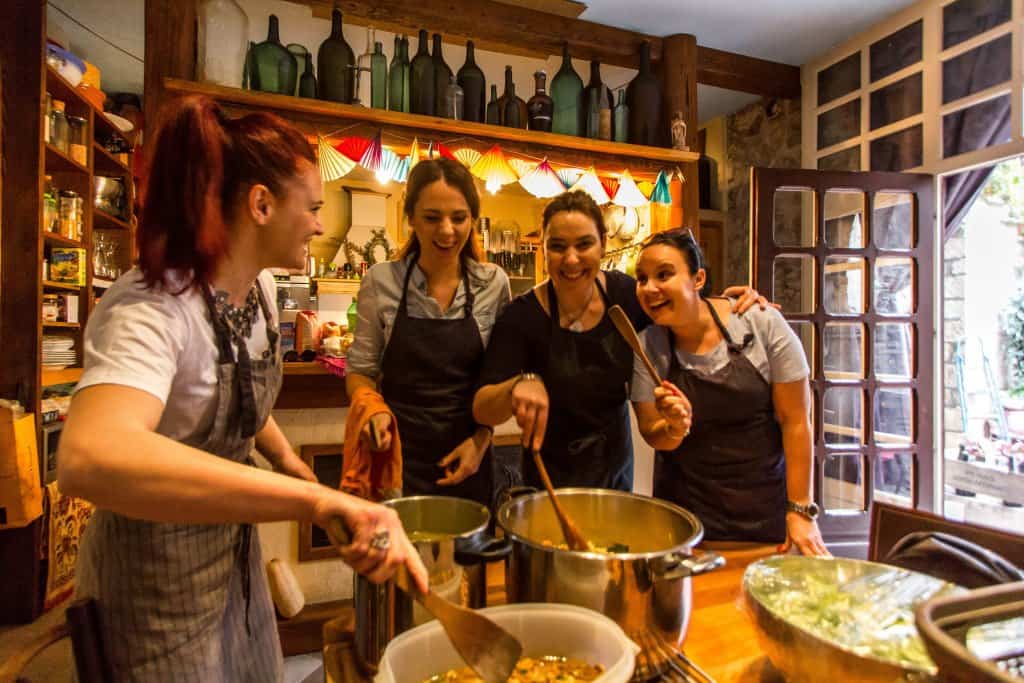 Four women smiling and preparing food -The International Kitchen Cooking Class