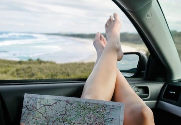 Bare feet sticking our of car window with open map in the foreground - tips for travelers - travel doesn't have to be expensive