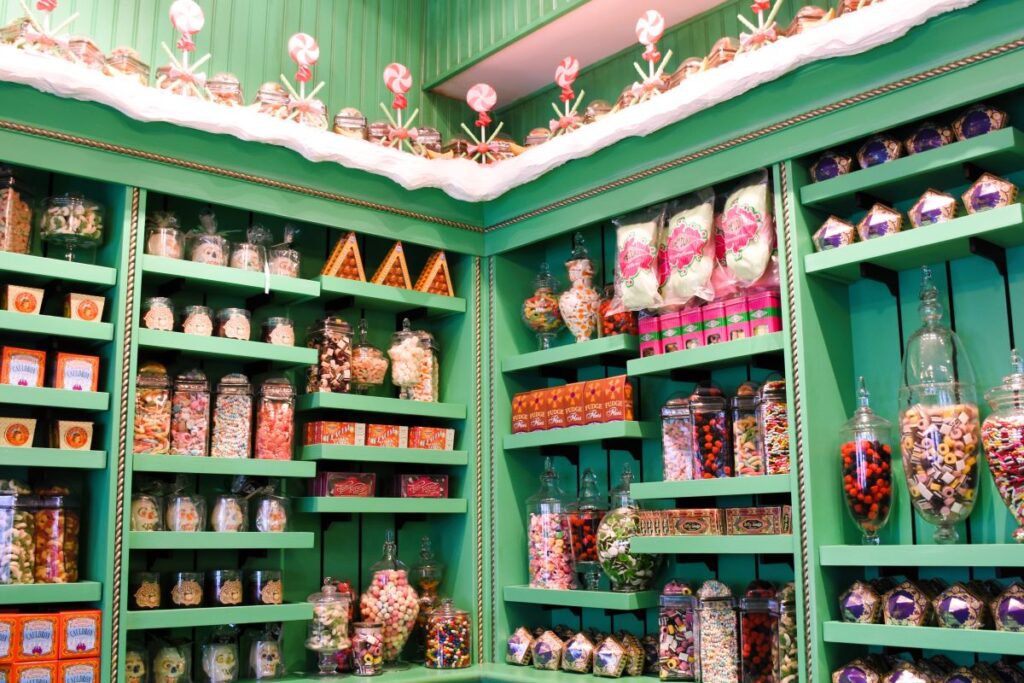 A bright green shelving unit holds Honeydukes Bert's Botts Beans and Harry Potter candy in jars and other packaging