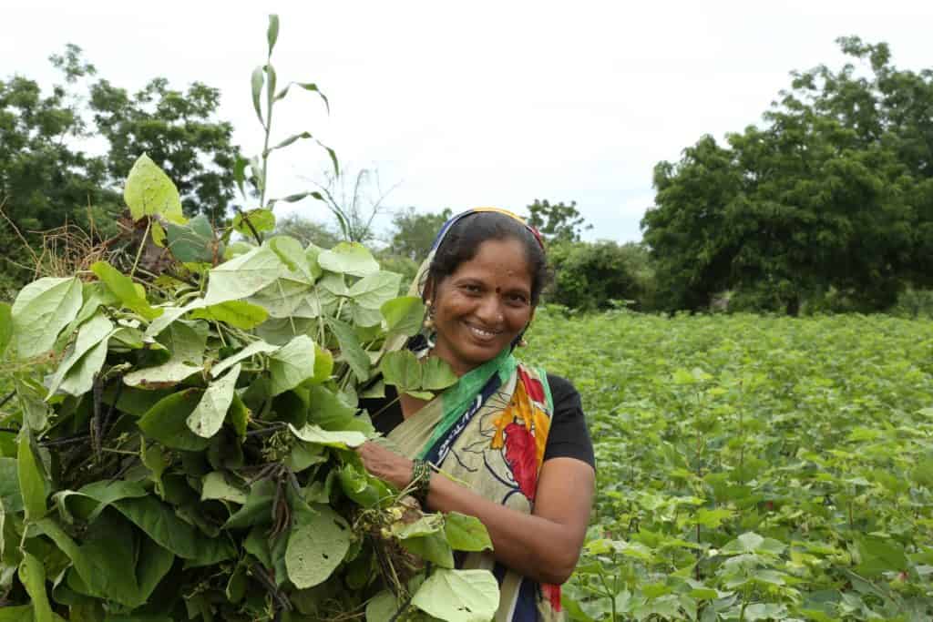 smiling woman in field holding crop