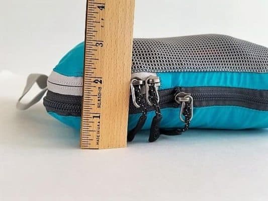 A compressed Packing Cube with ruler next to it showing Full Zipped Compression and how much space is saved.