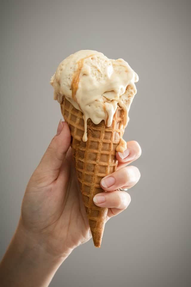 person's hand holding a dripping ice cream cone
