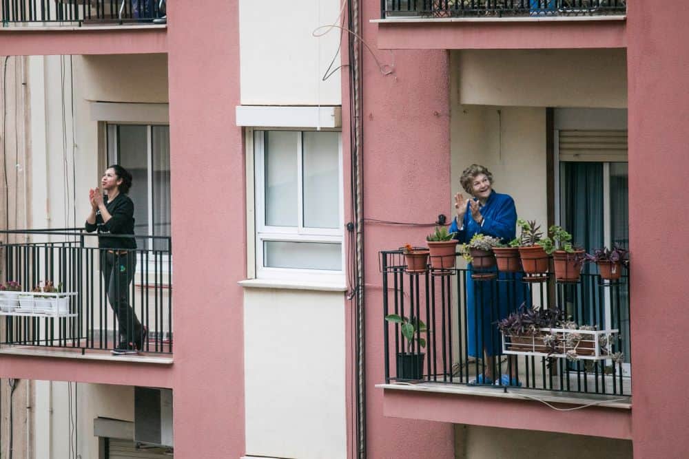 two neighbors on balconies smiling and singing