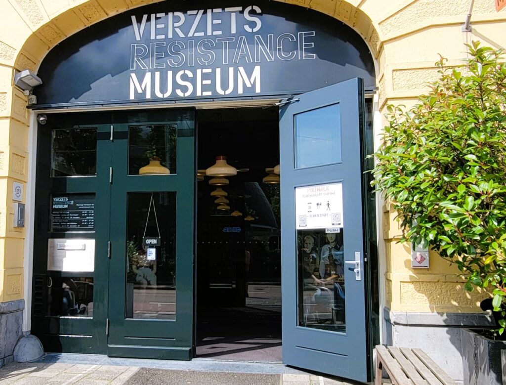 Entrance to beige stone building with arched doorway. Words above the open door are "Verzets Resistance Museum" the Dutch WWII Resistance Museum in Amsterdam 