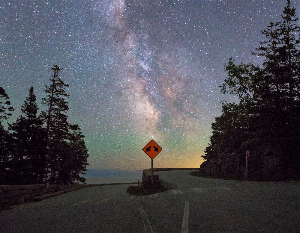 A fork in the road with stars above and trees beside the road. USA Road Trip