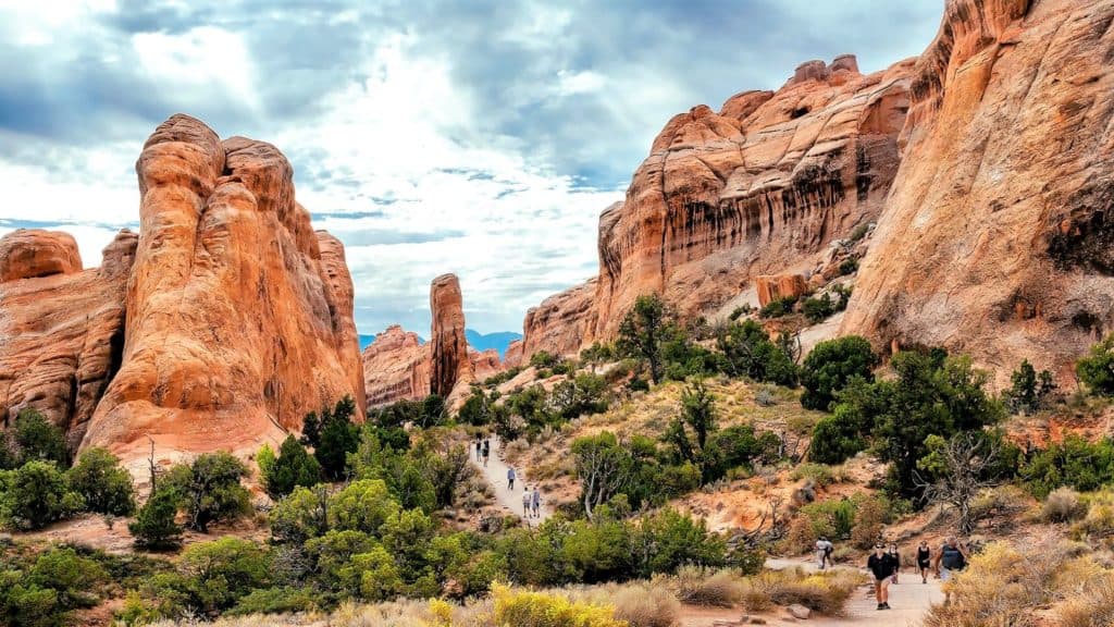 Hikers on a trail surrounded by red rock formations in Arches National Park