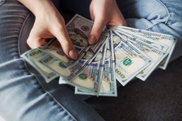 woman holding US money - dollars, hundred dollars