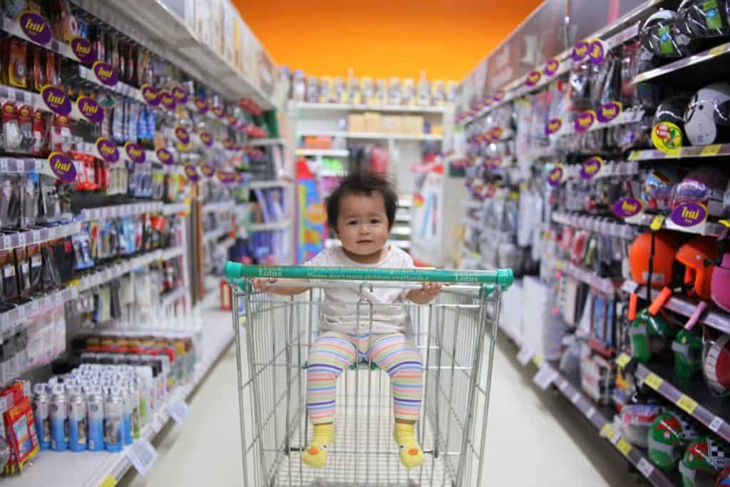 Smiling Asian child in grocery cart in grocery store