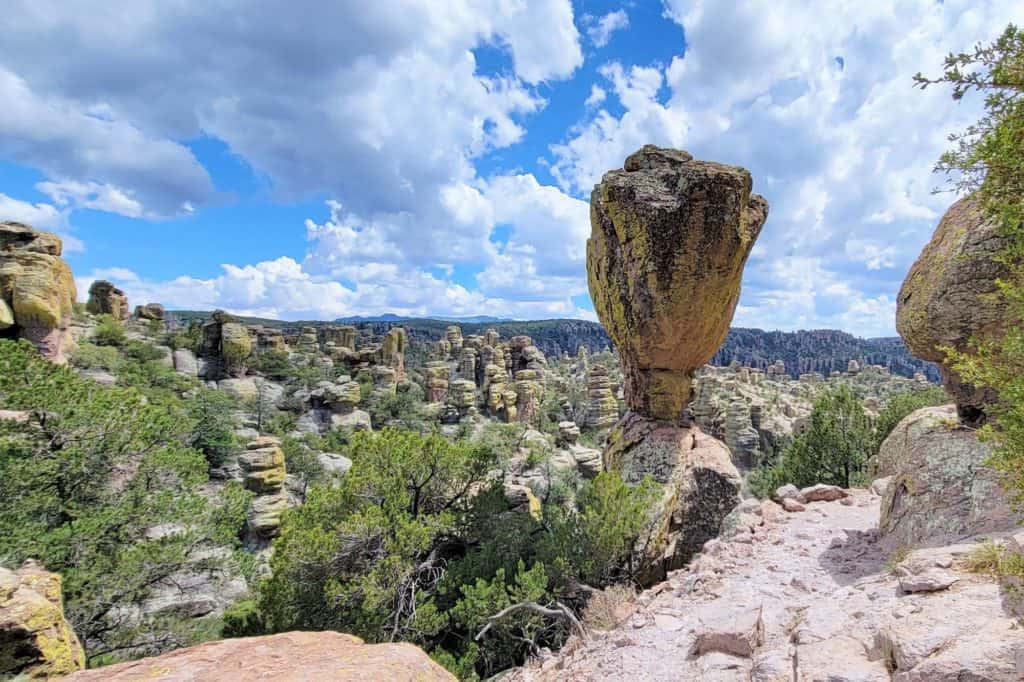 Massive boulder balancing on another. Many rock formations and mountains in the distance at Chiricahua NM