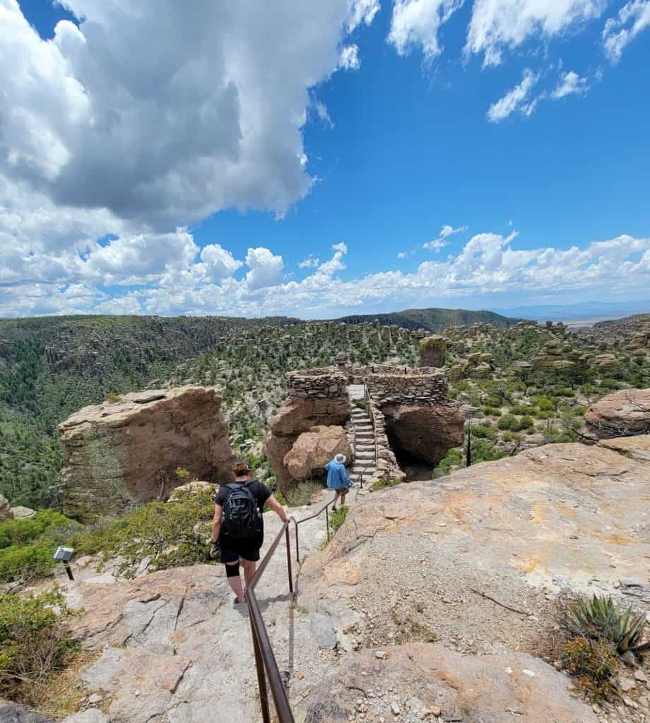 Man and woman climbing down rock steps to a canyon overlook in Chiricahua National Monument