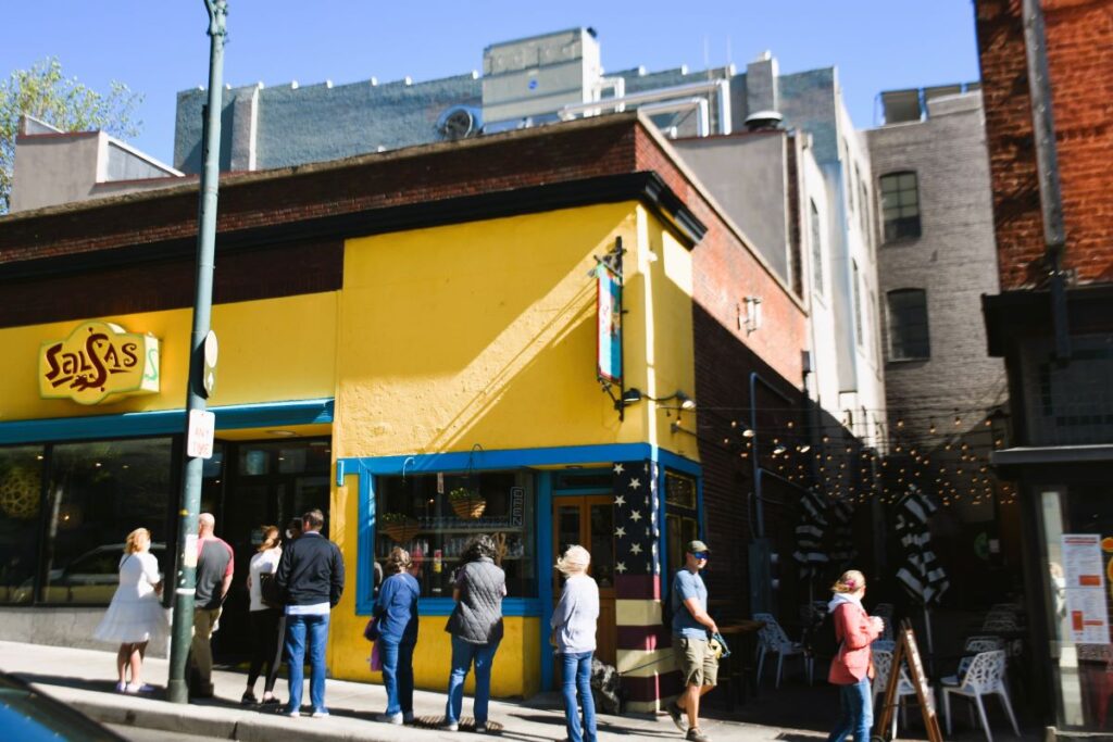 A line of men and women stand outside a yellow building waiting to get in. The building is Salsa's Mexican and Caribbean restaurant in Asheville. We visited on a North Carolina road trip.