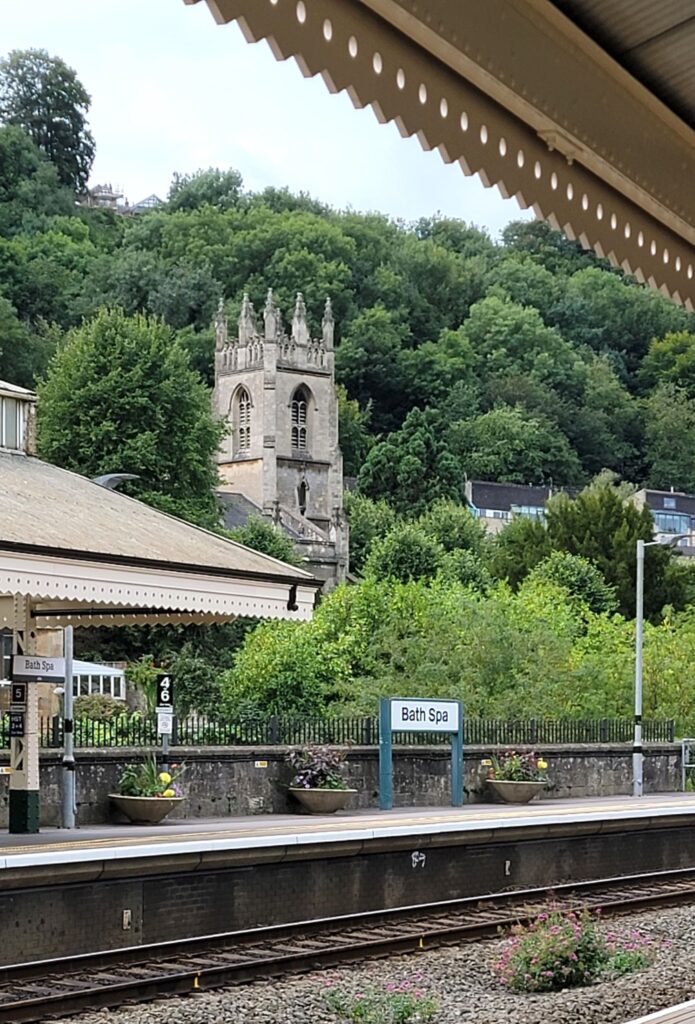 Train track at Bath Spa , UK railway station with building and trees in the background