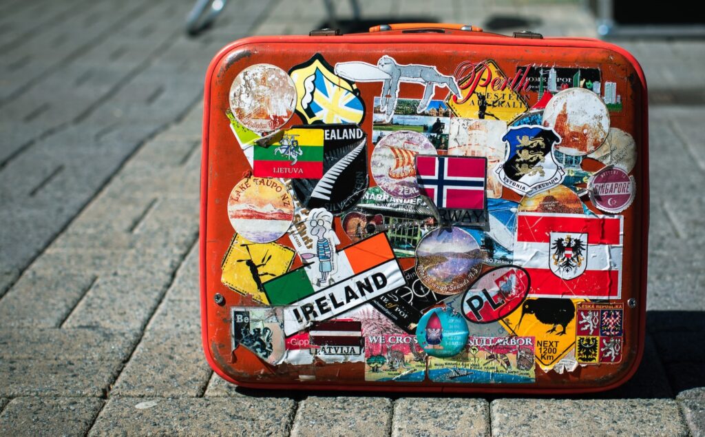 Orange suitcase with travel stickers from around the world stuck to it
