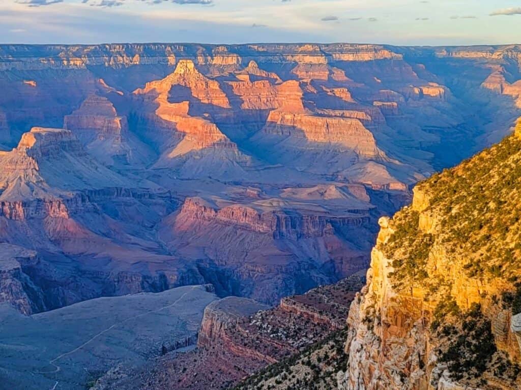 The majestic Grand Canyon in northern Arizona at sunset. Canyon walls are shades of purple and orange.