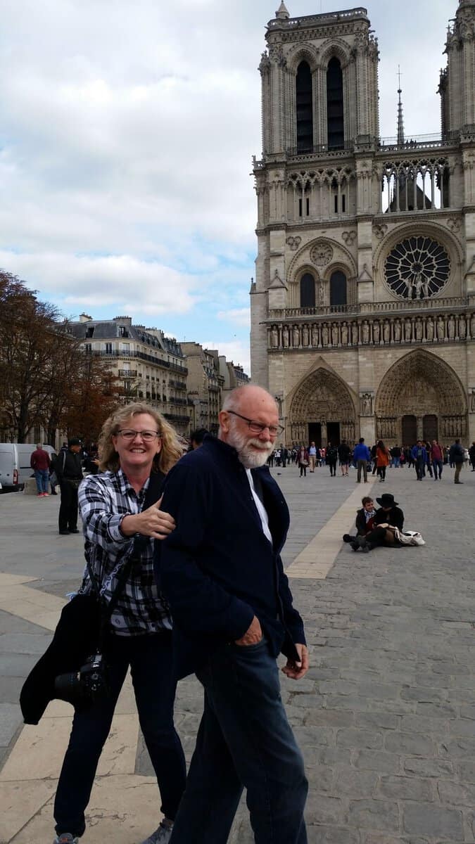 (Man) Terry and (woman) Nancy laughing in front of Notre Dame Cathedral in Paris, France. This was one of my great successes in trip planning for Europe.