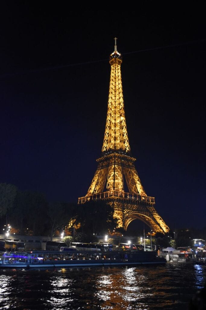 Eiffel Tower in Paris France lit up at night with lights reflecting in the river Siene