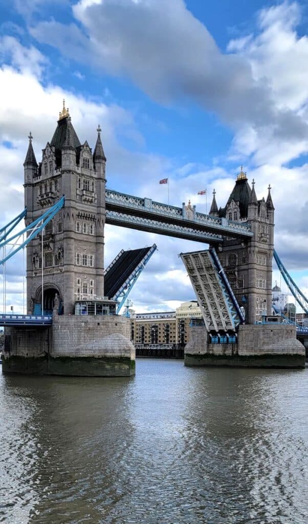 The two towers of Tower Bridge in London with drawbridge open. Blue skies with fluffy clouds