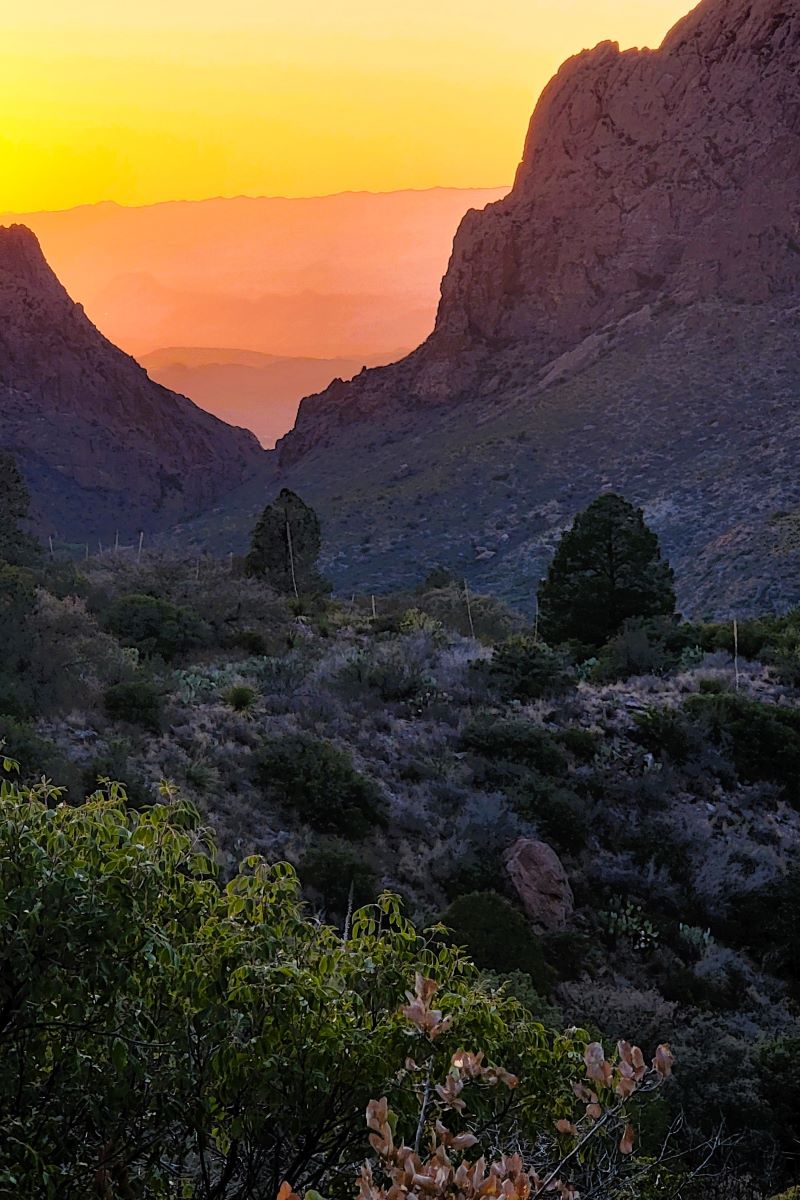 Sunset in colors of red, orange and yellow seen between two large rock formations near Window View Trail in Big Bend National Park, Texas.