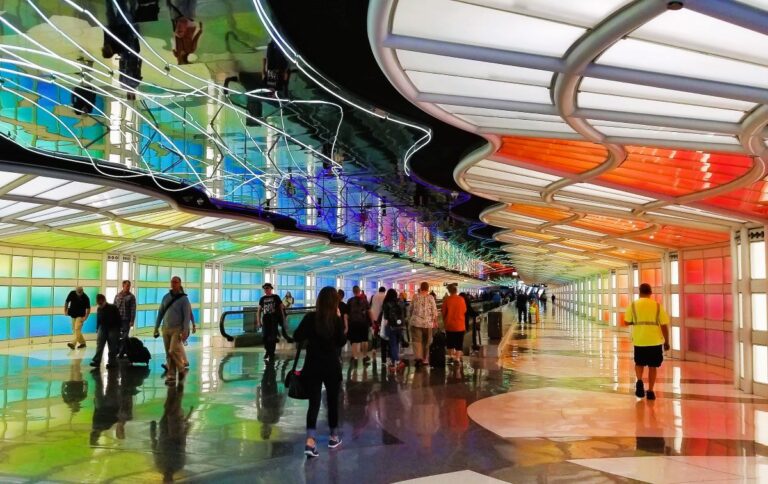 People walk with luggage through a colorful airport terminal at Chicago Airport.