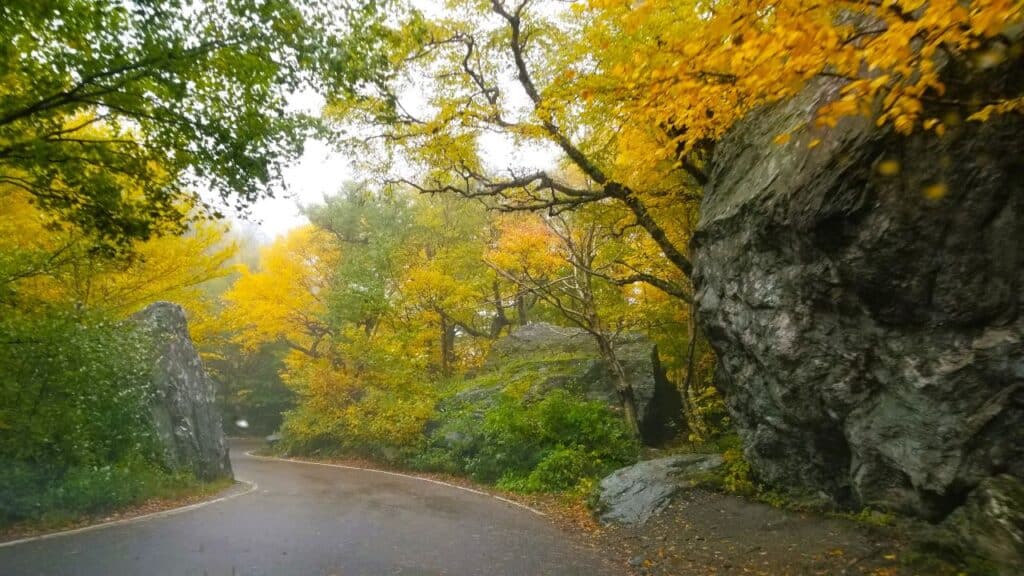 Smuggler's Notch Scenic drive in Stowe Vermont - beautiful fall colors of gold, orange and green trees line the narrow curvy mountain road.