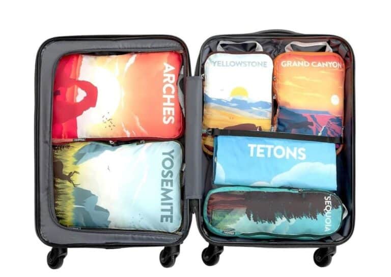 Carry-on suitcase with 6 different compression packing cubes inside. Each with a different national park design on the outside.