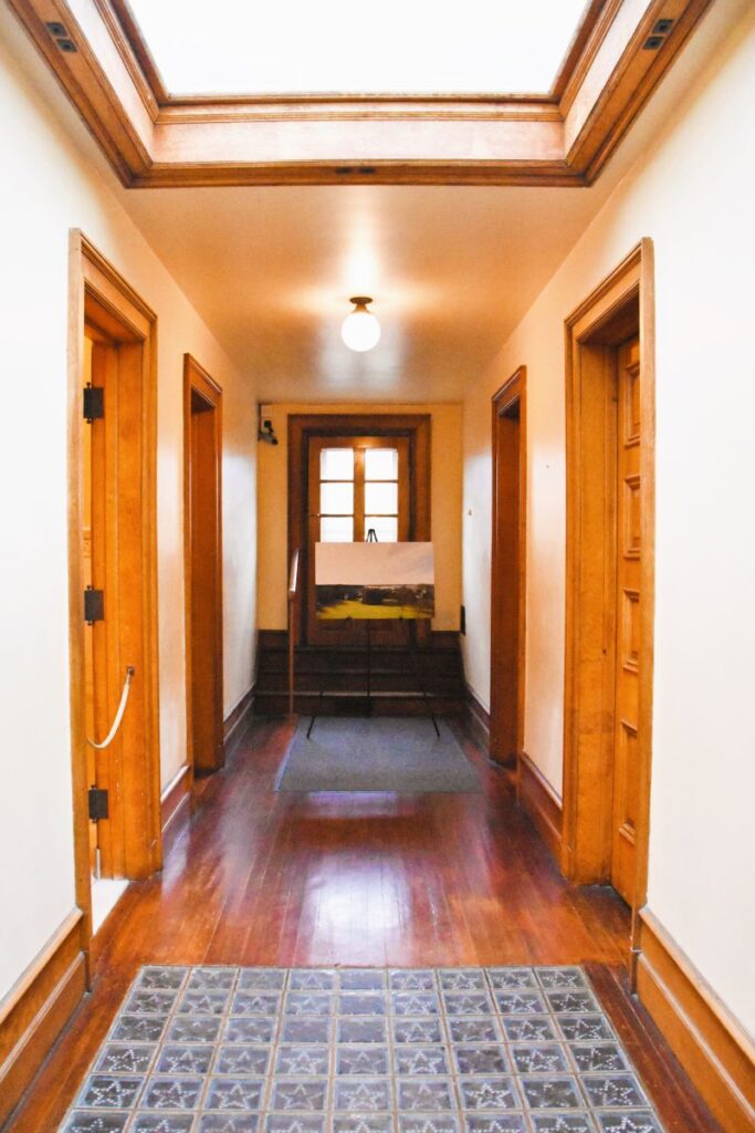 The hallway in the servant's quarters on the 3rd floor of the Elms Mansion - Newport, Rhode Island. A window is at the end of the hall. Floors are wood and there is a skylight in the ceiling. Part of the floor also has glass blocks to allow light from above into the 2nd floor.