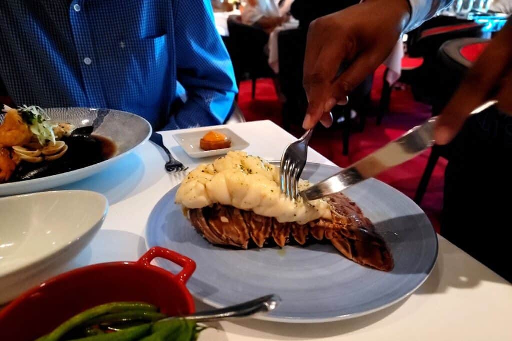 A waiter removing lobster from its shell at dinner at Rudi's Sel De Mer Seafood restaruant onboard a Holland America cruise ship.